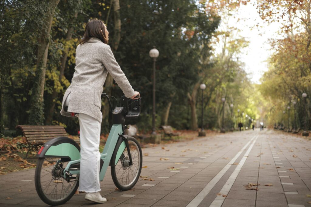 Woman ready to ride a bike on city park, rear view, copyspace. Purposes, objetives, new road concept
