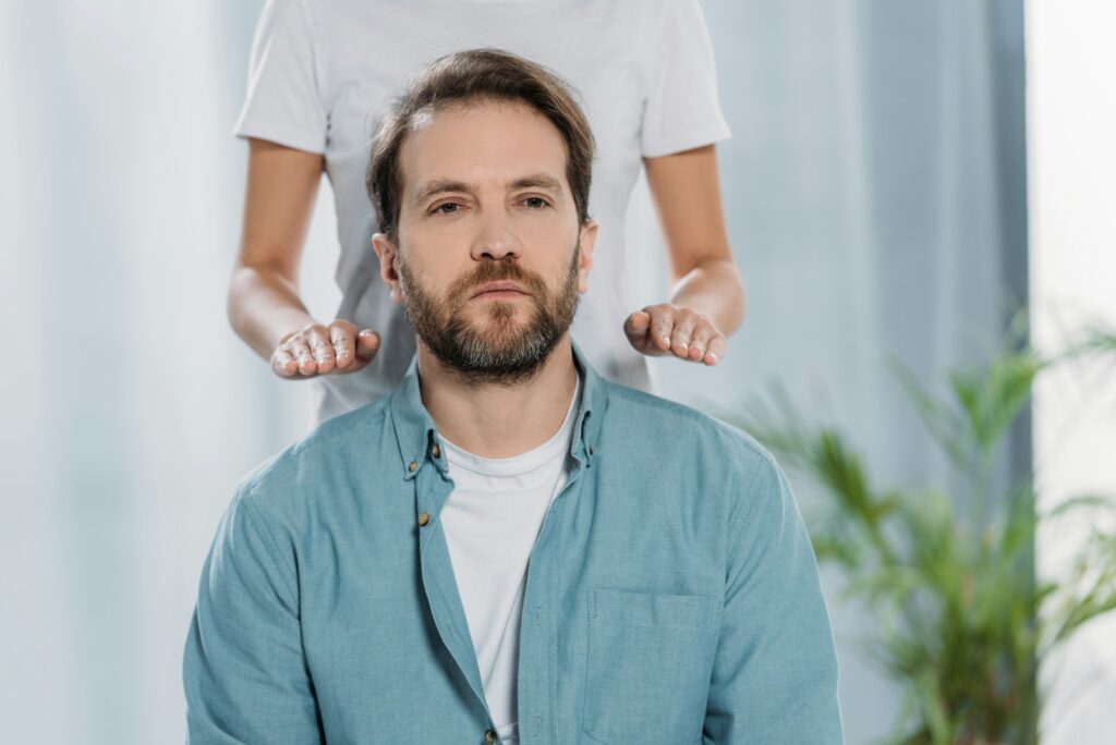 cropped shot of peaceful bearded man receiving healing reiki therapy