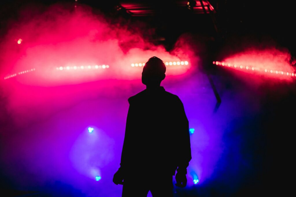 the silhouette of a man is surrounded by a smoke and colorful lights